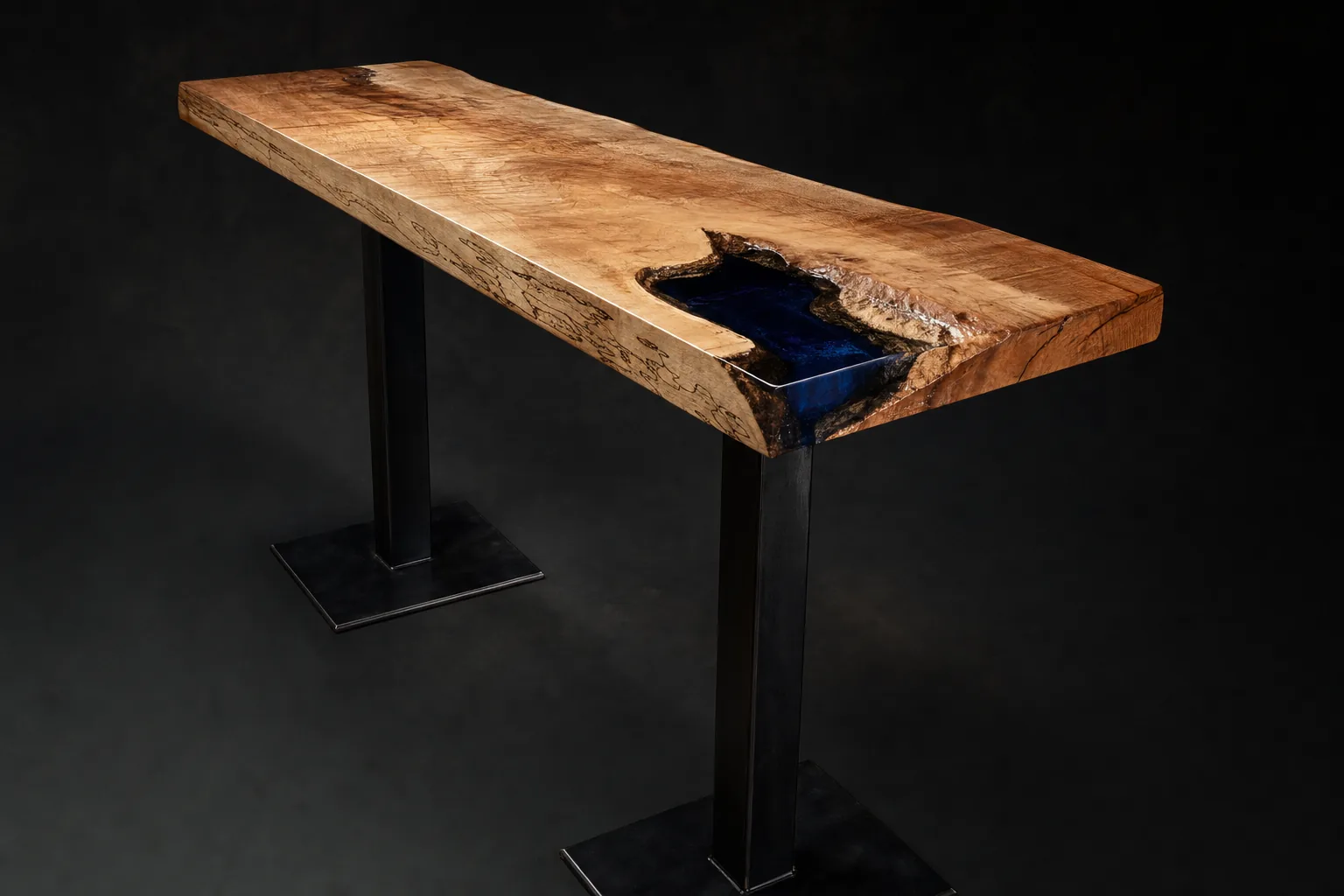 Spillway bar table, three-quarter view: big-leaf maple rail with ambrosia figure and a deep navy resin pour breaking over an edge void, blackened steel columns