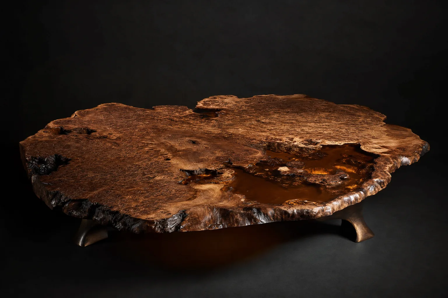 Stillwater coffee table, three-quarter view: dense walnut burl slab with amber resin pooled in its voids, low cast bronze feet, charcoal backdrop